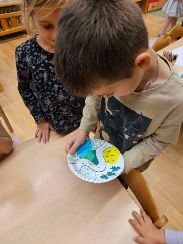 Děti si vyzkoušely magnetickou dráhu, když na papírový tácek s nakreslenou dráhou položily kancelářskou sponku a pohybovaly magnetem, který se dotýkal spodní části tácku   